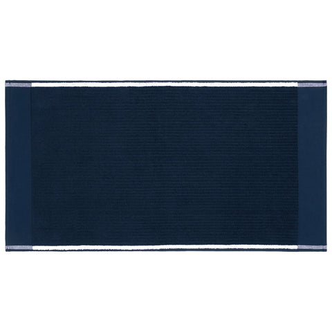 A dark blue towel lies flat showcasing a textured surface with white trim on the edges indicating its use in a bathroom or laundry setting for drying or decoration