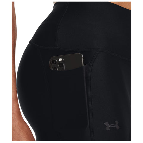 Black athletic leggings with a smartphone tucked into a side pocket are shown. The context suggests an active environment, suitable for exercise or casual wear. An Under Armour logo is visible.