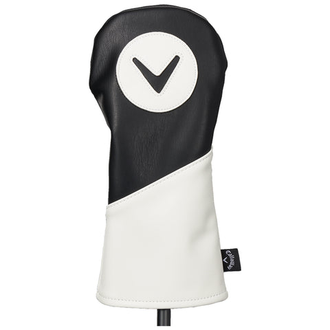 A black and white golf club headcover stands upright displaying a circular logo featuring a downward arrow symbol within a white circle against a black background in a neutral setting.