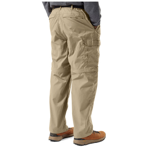 Khaki cargo pants are being worn by a person standing with hands in pockets in a casual setting complemented by brown hiking boots and a gray long-sleeve shirt.