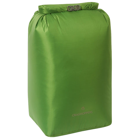 A green dry bag stands upright with a secure closure at the top, designed for waterproof storage during outdoor activities, suitable for camping or hiking environments.