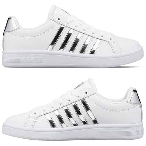 White athletic shoes feature a sleek design with shiny silver stripes on the sides and a textured sole, positioned against a plain background highlighting their clean aesthetic.