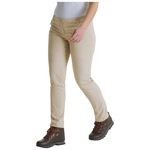 A person walks wearing light beige pants and brown hiking boots with orange laces in a neutral setting. The outfit suggests casual outdoor activity or adventure.