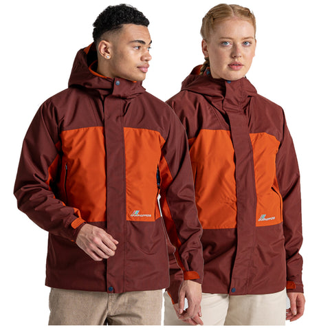 A man and a woman wear matching waterproof jackets in brown and orange colors. They are standing side by side, looking at each other, with a neutral background.