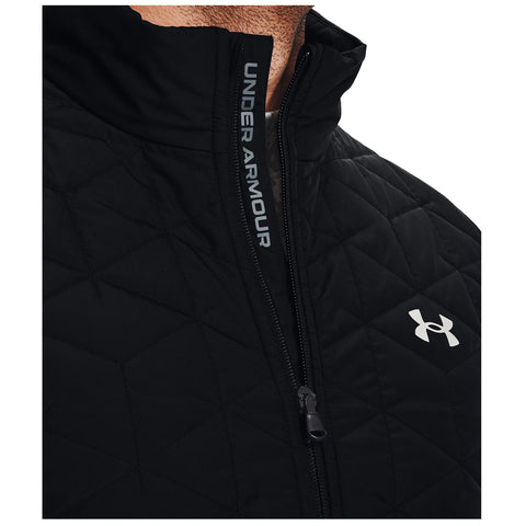 A black quilted jacket featuring a high collar and a zippered front is being worn. The brand name Under Armour is visible along the zipper and a logo is on the chest.