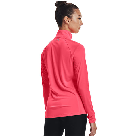 A person wears a bright pink long-sleeve shirt, gazing to the side, standing in an undefined space, emphasizing a sporty, active appearance. The shirt has a stand-up collar.