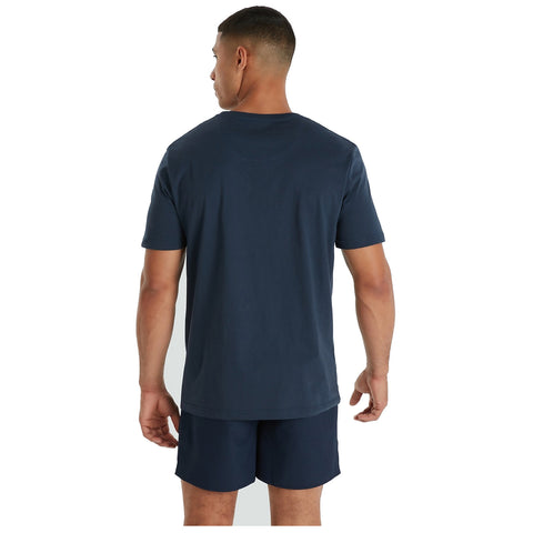 A person is standing with their back to the viewer wearing a dark blue t-shirt and matching shorts in a neutral background environment.