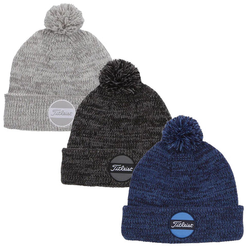 Three knitted beanies displayed side by side featuring a pompom on top each hat showcasing different colors grey black and navy with circular branded patches at the front