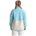 A person wearing a two-toned fleece jacket is standing with their back to the viewer. The upper part of the jacket is light blue and the lower part is cream.