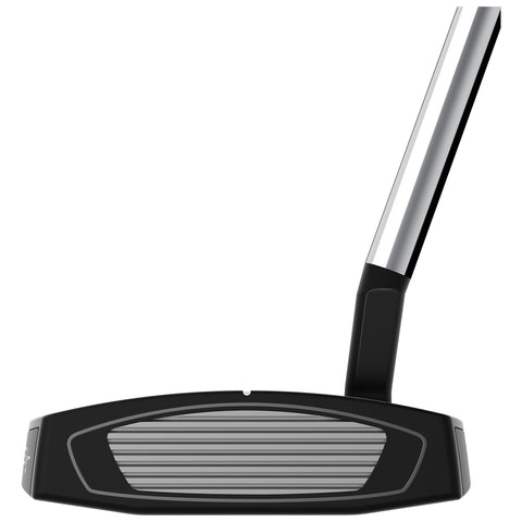 A black and silver golf putter rests with its flat face and grooves facing forward while the polished shaft rises vertically from the club head in a neutral background.