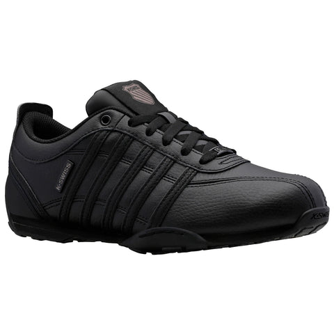 A black athletic shoe with a smooth leather finish displays multiple horizontal stripes and a logo on the tongue sitting on a simple white background showcasing its design and style.