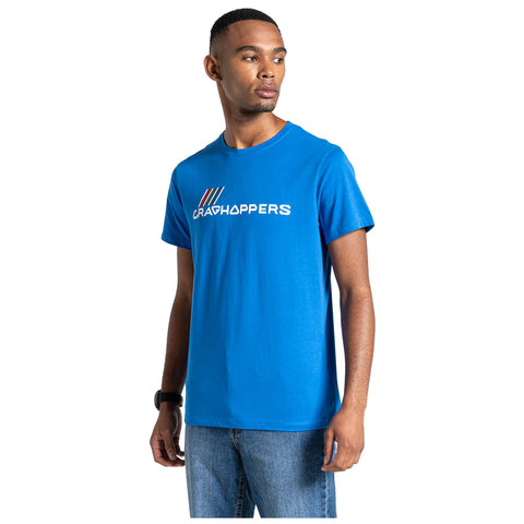 A young man stands wearing a bright blue t-shirt with the word "CRAGHOPPERS" printed on it in white. He has a serious expression and is positioned against a plain background.