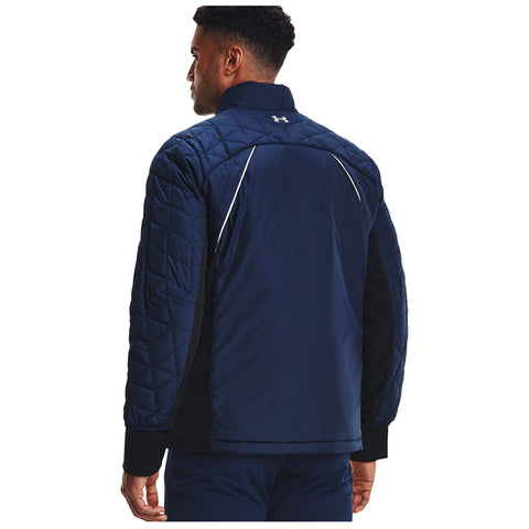 A man wearing a navy quilted jacket is standing with his back facing the viewer in a neutral setting showcasing the jacket's design and texture.