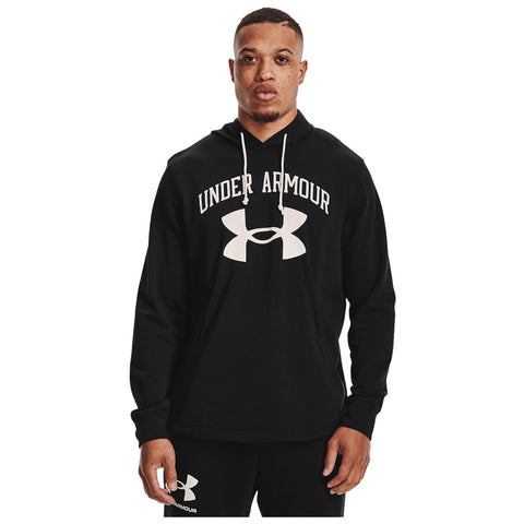 A person stands wearing a black hoodie with "UNDER ARMOUR" printed above a large logo the background is plain white giving a clean focus on the clothing and individual