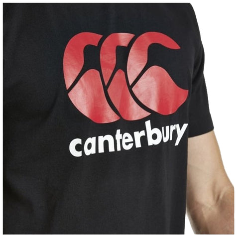 A black t-shirt displays a large red logo with three intertwined shapes above the word canterbury in white text while being worn by a person showing their arm