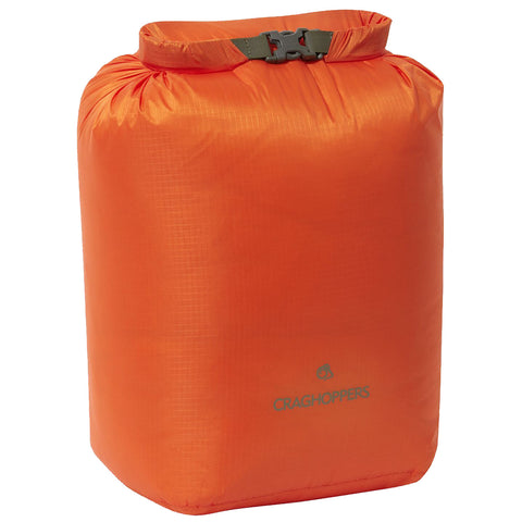 An orange dry bag stands upright with a folded top and a secure buckle closure it is likely designed for outdoor activities to keep contents dry and protected.