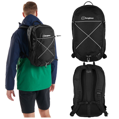 A black backpack is securely worn on the back of a person in a blue and green jacket outdoors, showcasing a sleek design with multiple straps and a logo.