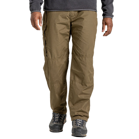 A person stands wearing light brown cargo pants and hiking boots, with a gray long-sleeve shirt, set against a plain background, suggesting an outdoor or casual environment.