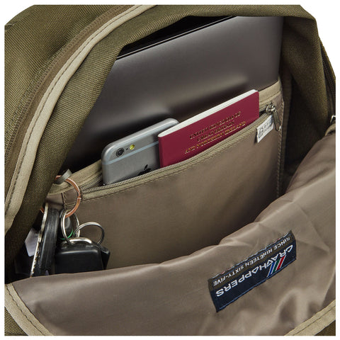 A backpack is open revealing a laptop inside along with a smartphone a passport and keys visible in the front pocket carrying a Carhartt logo