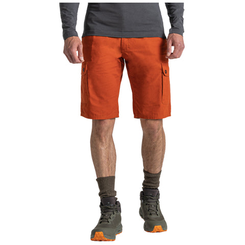 A person stands wearing orange cargo shorts and gray socks with green hiking shoes. They are dressed for an outdoor activity. The context suggests a casual, adventurous setting.