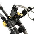 A black and yellow tool attachment features plastic components and metal cables is positioned on a gray frame suggesting assembly or adjustment in a workshop or home setting.