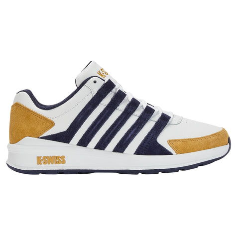 A sporty sneaker features a white body with navy stripes and a tan suede heel. It is positioned sideways displaying its design and branding in a clean, well-lit environment.