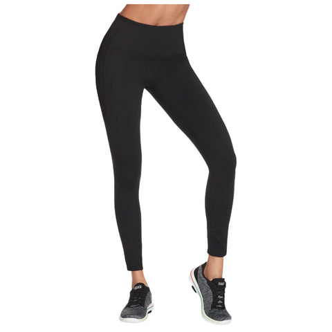 Black leggings are worn by a person standing in a neutral pose wearing athletic shoes in a simple indoor setting without additional context or distractions