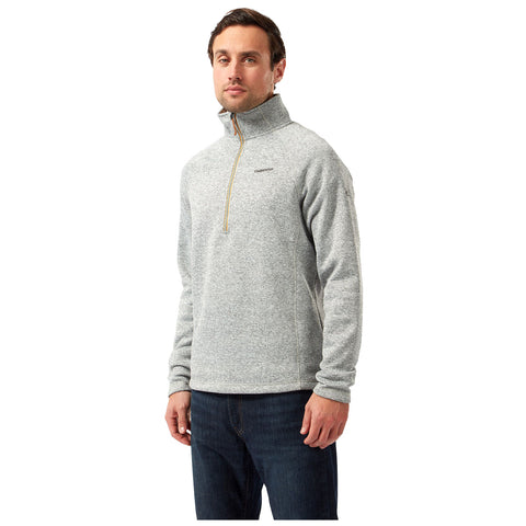 A man stands wearing a gray zip-up fleece pullover paired with dark jeans. He has a neutral expression and is posed against a plain white background.