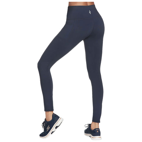 Navy athletic leggings are being modeled by a person standing in a slight pose on a neutral backdrop wearing navy sneakers showcasing a streamlined silhouette suitable for fitness activities.