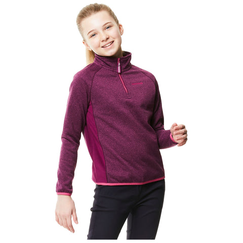 A girl is smiling and posing while wearing a purple zip-up fleece top with pink accents and black pants in a neutral background.