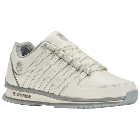 A white athletic shoe with grey accents rests on a flat surface featuring a sleek design with multiple stripes and a logo on the side, suitable for sports or casual wear.