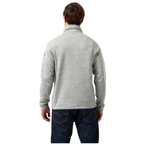 A man is standing with his back facing the viewer wearing a gray fleece jacket and dark jeans in a plain white background.