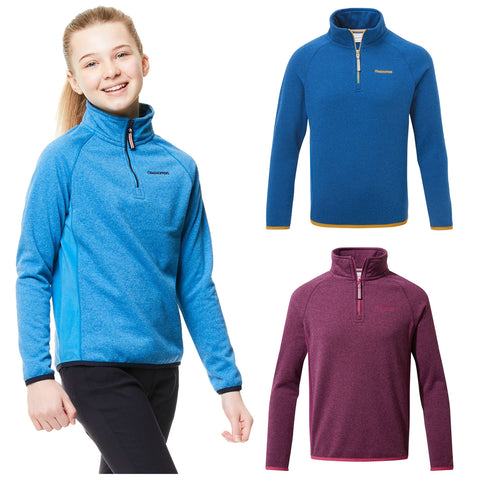 A young girl in a blue fleece pullover smiles while walking. Two additional fleece pullovers in blue and burgundy are displayed beside her.