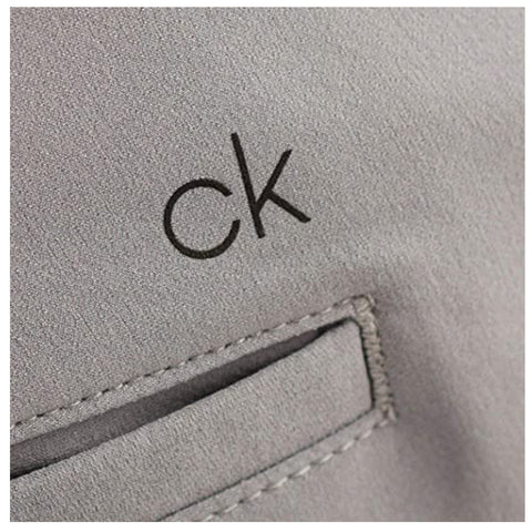 A gray fabric with a visible logo reading ck is shown near a small pocket featuring a stitched border in a clean and minimalistic context.