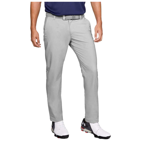 Gray pants are being worn by a person standing upright with one hand relaxed at their side while wearing sporty shoes and a navy shirt with a belt in a neutral setting.