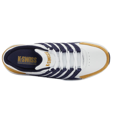 A white athletic shoe with navy blue and gold accents sits against a plain background showcasing its laces and branding indicating the shoe is designed for court sports.