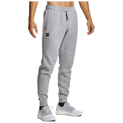 A person stands facing away wearing gray sweatpants and white athletic shoes with the setting featuring a neutral background that emphasizes their casual attire.