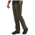 Craghoppers Mens Kiwi Pro II Walking Trousers A person stands with one leg slightly forward wearing olive green pants and black shoes while one hand is in their pocket in a plain background.