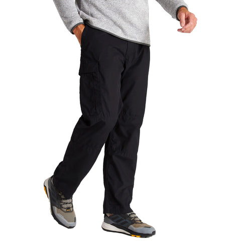 A person is walking, wearing black cargo pants and grey athletic shoes. The setting is neutral and uncluttered, focusing on the individual's casual and active outfit.