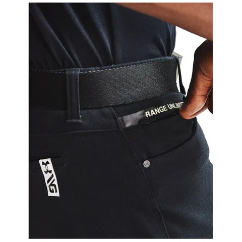 A person's hand is positioned near the waistband of black pants displaying a label that reads RANGE UNLIMITED in a casual setting highlighting the pants' design and functionality.