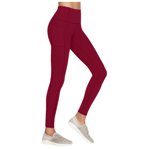 Leggings in a deep red color are worn by a person standing with one leg slightly bent while wearing light gray athletic shoes in a neutral setting.