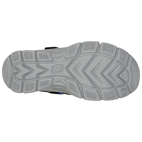 A sneaker’s outsole displaying a textured surface with a zigzag pattern and a central logo features traction elements designed for grip on various surfaces in an athletic context.