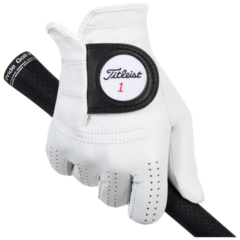 A white golf glove grips a textured black golf club handle showcasing a logo patch labeled Titleist 1 providing a sense of preparation for an upcoming swing in a golfing environment.