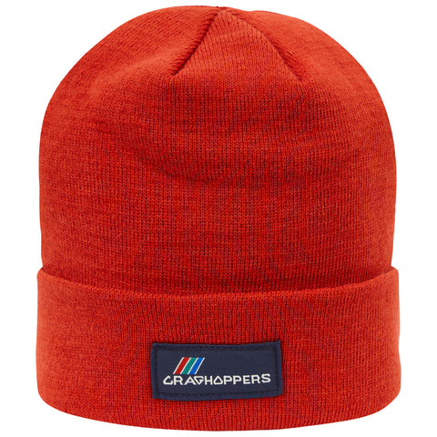 A bright red beanie hat sits upright showcasing its knitted texture and a folded cuff featuring a branded patch indicating the name Craghoppers