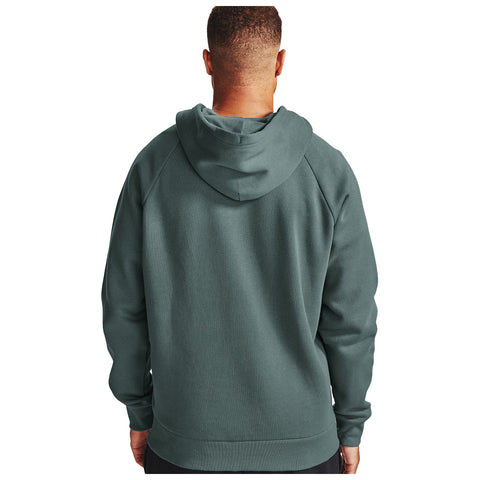 A person wearing a green hoodie stands with their back to the viewer in a neutral space, suggesting a casual and relaxed atmosphere. The hoodie features a hood and a simple, comfortable design.