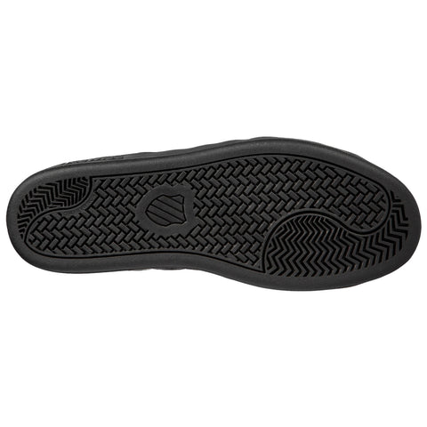 A black sneaker sole rests flat showcasing a textured pattern with various grooves and ridges designed for traction in diverse environments providing stability and grip during movement