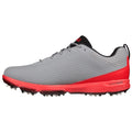 A gray athletic shoe with red accents features a textured upper and a durable sole equipped with spikes designed for traction on turf or grass surfaces.