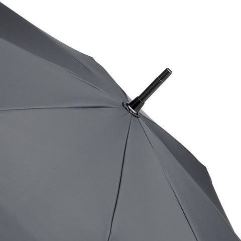 A black umbrella is opened with its canopy visible and a central shaft protruding from the top in a minimalistic and neutral background highlighting its design.