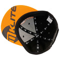 A baseball cap featuring an orange brim and black body is positioned upside down showing its interior design and branding elements on the inner lining and tag