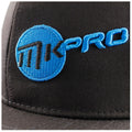 A black baseball cap features a prominent blue circular logo with the letters MK embroidered in black and the word PRO in blue positioned to the right of the logo